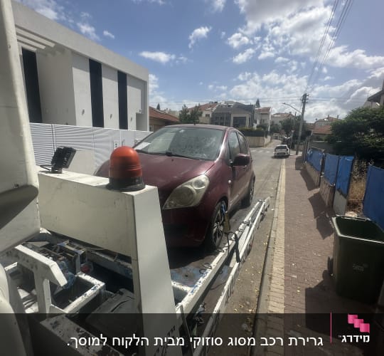 רכב אדום על גרר לבן ברחוב